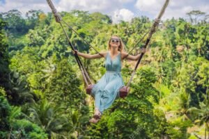 Young woman swinging in the jungle rainforest of Bali island, Indonesia. Swing in the tropics. Swings - trend of Bali